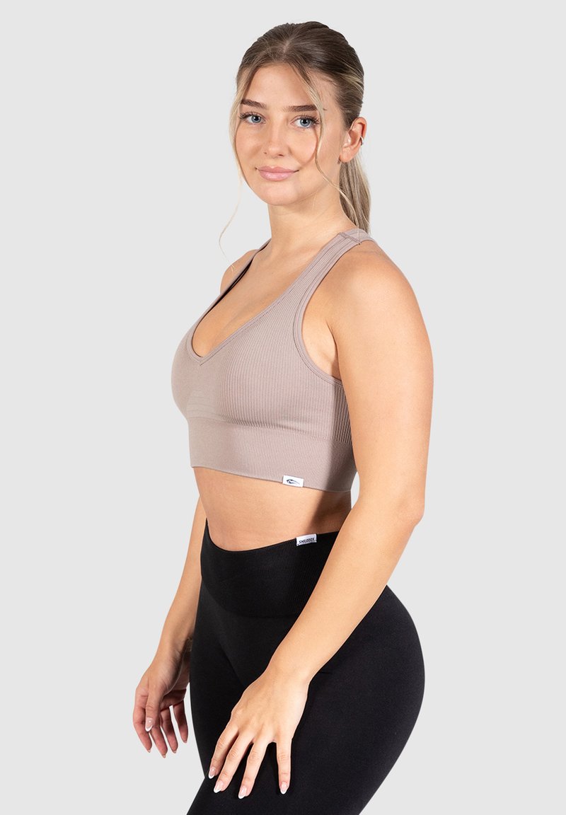 Top corto de canalé beige con tirantes anchos y un diseño de escote en V. Combinado con leggings negros de cintura alta. Textura suave, con un diseño minimalista.