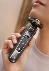 Philips elektrisch scheerapparaat met een strak zilver- en zwart ontwerp, ergonomische grip, aan/uit-knop en een afgeronde scheerkop voor een nauwkeurige afwerking.