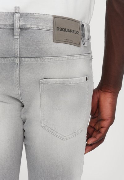 Jeans en denim gris clair avec une finition texturée, arborant une étiquette en cuir DSQUARED2 et une poche arrière avec un petit détail de conception discret.
