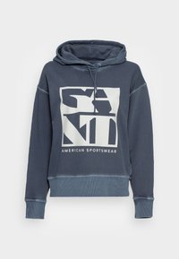 Marinblå hoodie i bomull med en stor grafik som har texten "AMERICAN SPORTSWEAR". Utsmyckad med ribbade muddar och fåll.