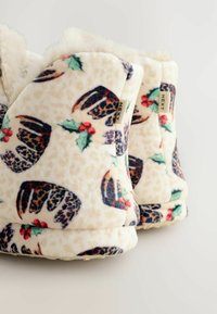 Fluffy hjemmesko i cremefarve med et festligt mønster af kristtorn og leopardprint. Blød tekstur med polstret design og struktureret sål.