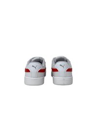 Zapatillas deportivas blancas con parte superior de cuero suave, acentos rojos en los laterales y un collar acolchado para mayor comodidad.