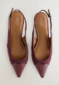 Burgundia slingback kontsad kõrged kontsad, terava ninaga, seemisnahast pealispind ja nahkdetailid. Varustatud reguleeritava pandlaga ja avatud külgedega, mis tagavad õhu läbilaskvuse.