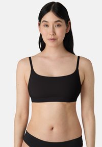 Zwarte, naadloze bralette met dunne verstelbare schouderbandjes en een vierkante halslijn. Zacht stof met een gladde textuur, geschikt voor dagelijks gebruik.