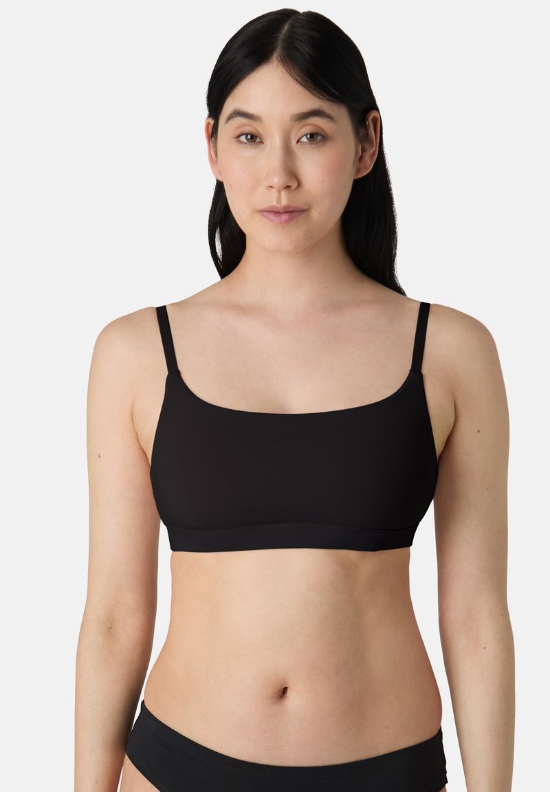 Zwarte, naadloze bralette met dunne verstelbare schouderbandjes en een vierkante halslijn. Zacht stof met een gladde textuur, geschikt voor dagelijks gebruik.