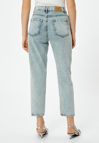 Ljusblå denimjeans med hög midja, rak ben, två bakfickor och en brun läderlapp vid bakdelen av midjan.