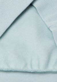 Felpa azzurra chiara con una texture a coste e un morbido rivestimento in pile. L'orlo presenta una finitura arricciata per una vestibilità aderente.