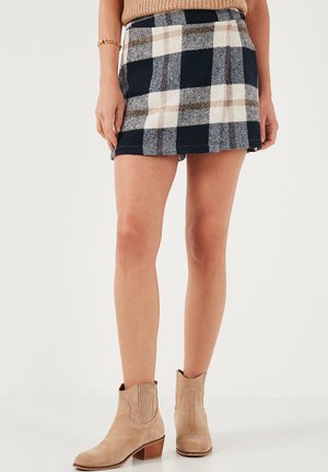 Marineblauwe, grijze en crèmekleurige geruite mini-jurk met een rechte zoom, voorzien van een soepele textuur en een aansluitende taille. Draagt met beige enkellaarsjes.