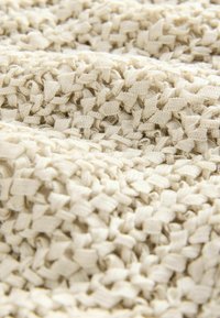 Beige szőtt anyag, melyen a szőtt csíkok mintázata kerül bemutatásra, lágy, enyhén kiemelkedő felületet képezve.