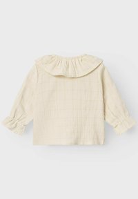 Camicia color beige chiaro con colletto arricciato, maniche lunghe con polsini arricciati e un sottile motivo a scacchi che attraversa il tessuto.