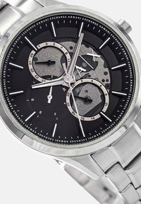 Roostevabast terasest kell musta diali, hõbedaste aktsentide ja kahe aladialiga. Märgistatud 'AX' ning detailsete tunni markeritega. Metalne käevõru disain.