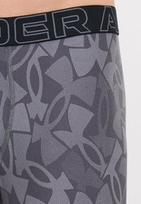 Férfi boxeralsó szürkében, hálószerű textúrával. Fekete elasztikus derékszíj "UNDER ARMOUR" logóval, geometrikus mintával kontrasztban.