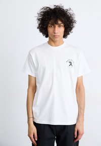 White cotton t-shirt with short sleeves and a round neck, featuring a small black graphic print on the left chest.