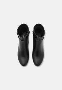 Botines de cuero negro con un diseño elegante, punta redondeada, textura suave y un acento de cremallera lateral.
