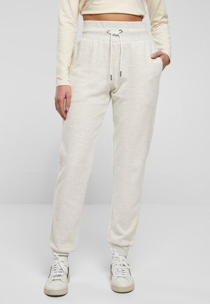 Lys beige joggebukser laget av myk, teksturert stoff. Har elastisk midje med snor og sidelommer. Tapered ben design.
