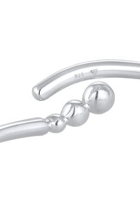 Armband i sterling silver med släta, böjda stavar och sfäriska element, med en polerad yta och märkt med "925" för äkthet.
