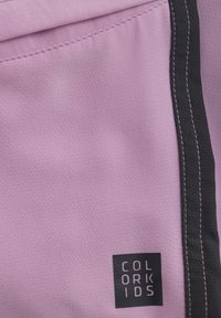 Lila tyg med en slät yta, med svarta stygn längs kanten. Etiketten säger "COLOR KIDS" i vit text på en svart bakgrund.