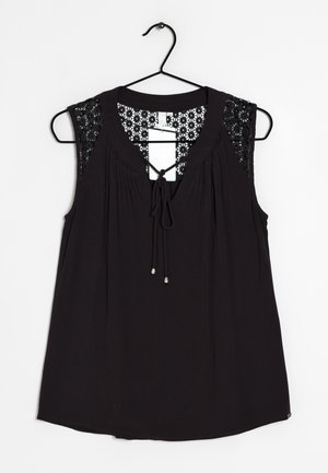 Czarna bluzka bez rękawów z koronkowymi kwiatowymi ramionami i wiązaniem z przodu, wisząca na czarnym wieszaku na białym tle.