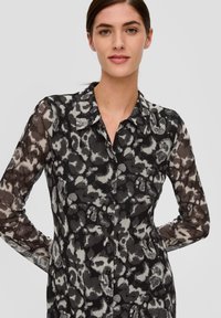 Durchsichtige Schwarz-Weiß-Tiermotiv-Hemdbluse mit Kragen und langen Ärmeln, aus einem strukturierten, leichten Stoff gefertigt.