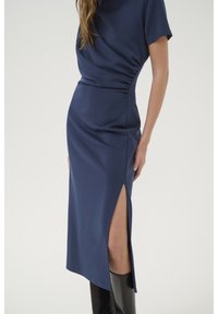 Navy blue short-sleeve fitted dress with a side slit, made of soft fabric, featuring gathered detailing on the waist and a smooth texture.