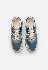 Blue and green sneakers with a beige sole and black accents. Textured fabric upper, thick white laces, and patterned inner lining visible.