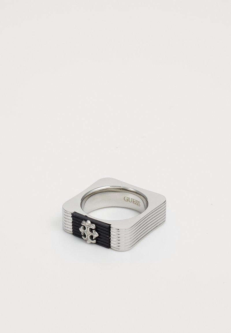 Square silver metal ring with black textured detail and a small silver decorative emblem, branded "GUESS" inside.