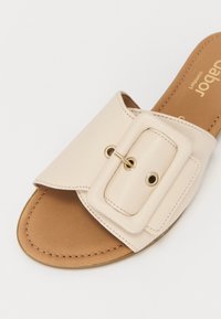 Infradito in pelle beige con una larga fascia e una grande fibbia in metallo dorato a contrasto, montata su una soletta imbottita color cammello.