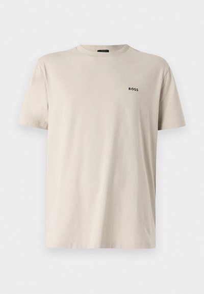 T-shirt en coton beige à col rond avec des manches courtes. Présente un petit logo "BOSS" noir sur le côté gauche de la poitrine. Texture lisse.