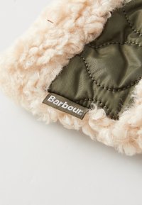 Beige nepbont buitenkant met daaronder een gequilt groene stof. Bevat een "Barbour" logo label in contrasterend bruin op de gestructureerde rand.