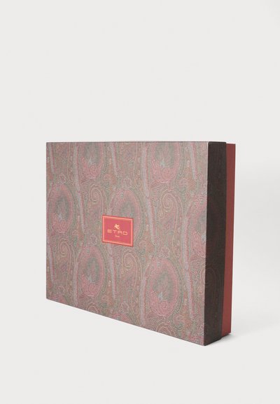 Boîte rectangulaire de créateur avec un motif cachemire complexe dans des tons roses et verts atténués, avec une étiquette rouge centrale portant un texte doré.