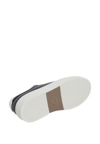 Svart lädersneaker med en texturerad vit gummisula, utrustad med en brun accentflik med logotyp. Lågprofil design och slät finish.