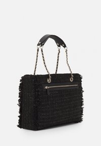 Czarna torebka z tweedu z frędzlami, łańcuszkowymi i skórzanymi uchwytami oraz przednią kieszenią na zamek. Teksturowana powierzchnia o wyraźnym kształcie.