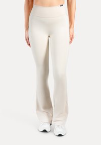 Beige, hoog getailleerde flared legging gemaakt van een gladde, rekbare stof. Voorzien van een brede tailleband en subtiele naden. Combineert goed met witte sneakers.