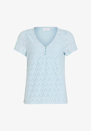 Blouse bleu clair à manches courtes avec col en V, détail boutons et tissu œillet à motif chevrons.