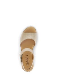 Beige sandal with woven upper, ankle strap and silver hardware. Soft footbed, round toe, and minimalist design for comfort and style.