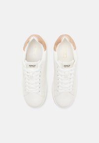 Paire de baskets blanches avec des lacets blancs et des accents dorés scintillants au talon, étiquetées "ONLY est. 1995" sur la languette.