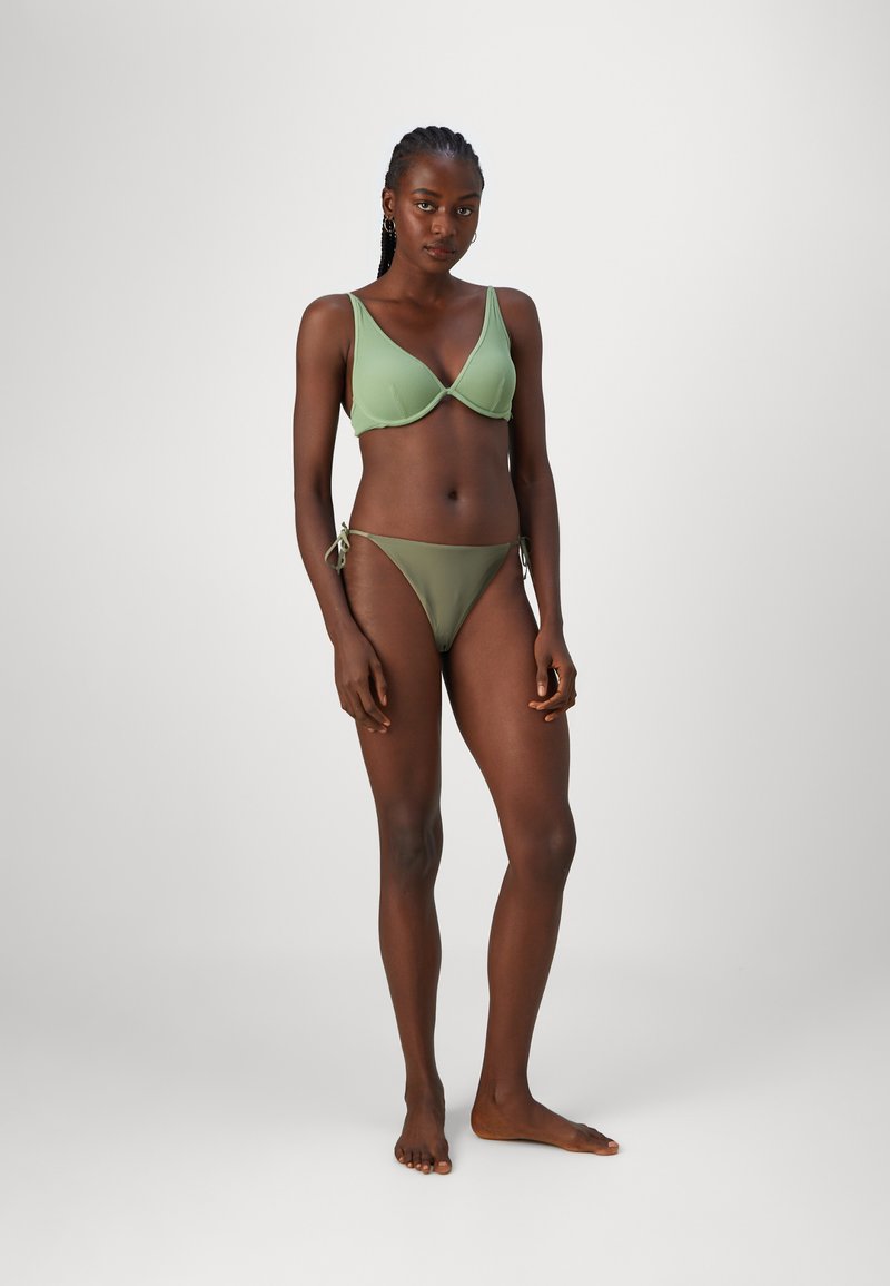 Zeleni rebrasti bikini z vrhom v obliki trikotnika z širokimi naramnicami in nastavljivimi spodnjimi hlačkami na vezalko, gladka tekstura, minimalističen dizajn.