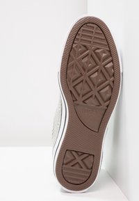Bruine rubberen schoenzool met een geometrisch textuurpatroon, witte zijwanden, zwarte afwerking en een bedrukt logo met de tekst "Converse All Star."