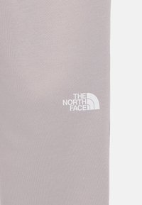 Gaišpelēkas legingi, kas izgatavoti no mīksta auduma, ar mazu baltu "The North Face" logo sānos. Gluda tekstūra, pieguļošs dizains.