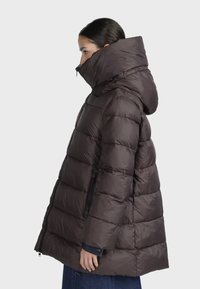 Giacca puffer marrone con colletto alto, tasche con zip e cappuccio; design trapuntato; texture liscia; lunghezza a metà.