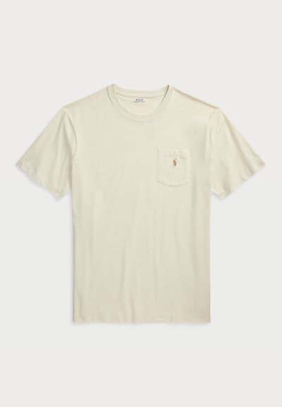 T-shirt à manches courtes et col rond en coton beige clair, avec une poche poitrine et un logo brodé dans une teinte contrastante.