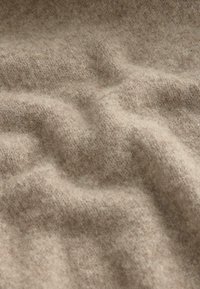 Material din lână bej, cu o suprafață moale și texturată, care prezintă variații subtile de culoare și pliuri delicate. Ideal pentru îmbrăcăminte sau tapițerie.