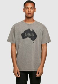 Grijze oversized T-shirt van katoen met een ronde hals. Voorzien van een zwarte silhouet van Australië en het woord "Australië" op de voorkant gedrukt.