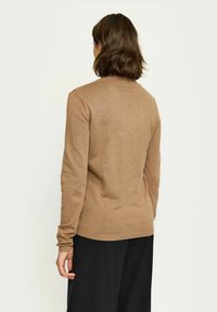 Maglione marrone in maglia con maniche lunghe e colletto a girocollo, caratterizzato da una texture liscia e un design aderente. Orlo e polsini a coste visibili.