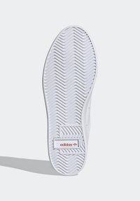 Vit sneakersula med ett fiskbensmönster för grepp, med en röd Adidas-logotyp och texturerade detaljer runt hälområdet.