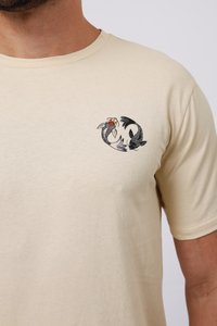 Κρέμ T-shirt με κοντά μανίκια, που διαθέτει σχέδιο καπνοψαριού σε μαύρο και κόκκινο χρώμα στην αριστερή πλευρά του στήθους. Μαλακή βαμβακερή υφή, στρογγυλή λαιμόκοψη.