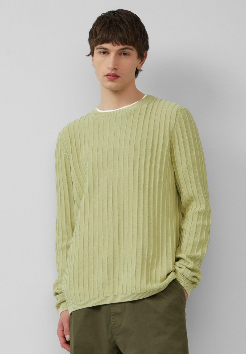 Hellgrüner gerippter Pullover mit langen Ärmeln und rundem Halsausschnitt, der eine feine Textur und eine lockere Passform aufweist, kombiniert mit olivfarbenen Hosen.