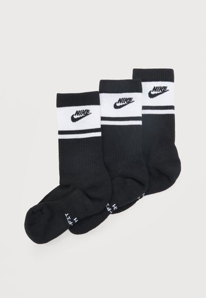 Három pár fekete-fehér Nike crew zokni fekete Swoosh logóval és dupla csíkokkal fent, átfedésben elrendezve fehér háttéren.