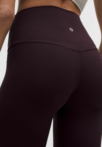 Visoko pasovi, bordo leggingi z gladko teksturo in kontrastnim šivanjem. Imajo majhen logotip blizu pasu.