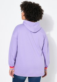 Levandulová mikina vyrobená z měkkého materiálu, s uvolněným střihem, oversized kapucí a vícebarevnými pruhovanými detaily na manžetách.